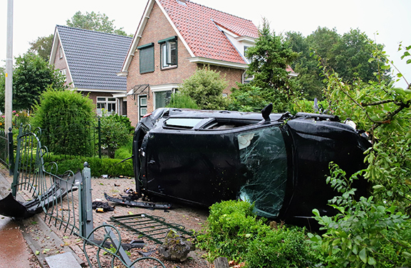 Auto ramt hekwerk en komt in tuin op zijkant tot stilstand