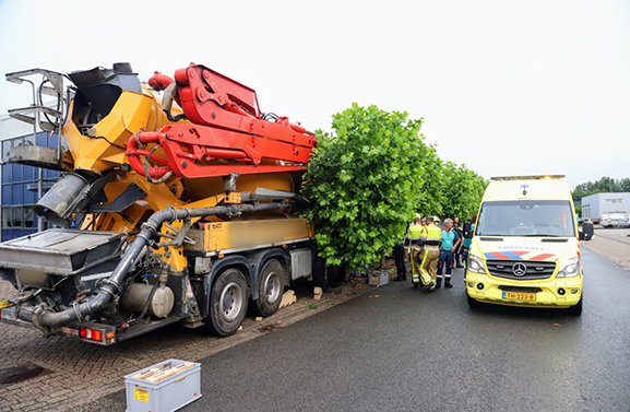 Chauffeur betonwagen rijdt tegen een boom en een zeecontainer